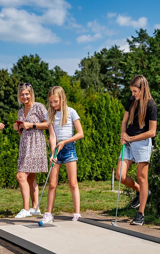 Familie spielt Minigolf
