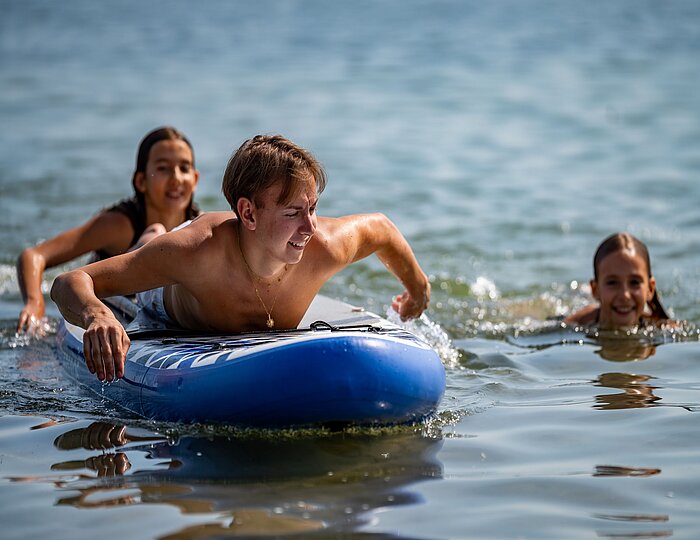 Kinder machen Stand-Up Paddling SUP am See
