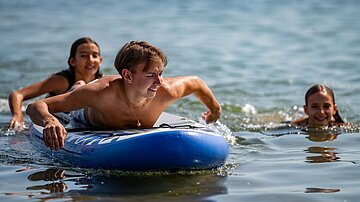 Kinder machen Stand-Up Paddling SUP am See